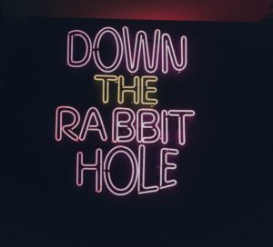 neon sign that says down the rabbit hole.